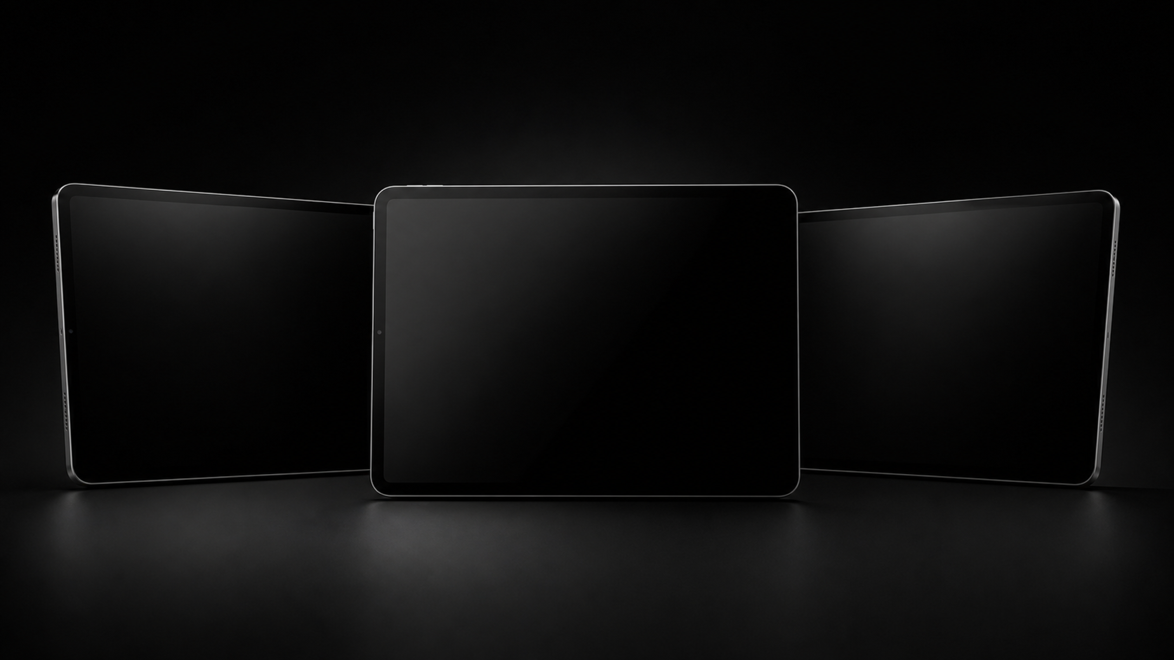 Three blank black tablets on a dark studio background